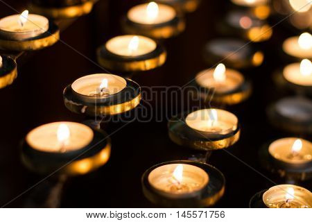 Rows of alight candles in a church that are lit by the congregation in remembrance of their loved ones.