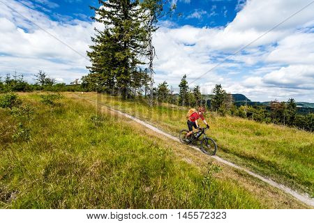 Mountain biking man riding on bike in summer inspirational mountains landscape. Rider cycling MTB on enduro trail path. Sport fitness motivation and inspiration. Rider mountain biker in summer woods.