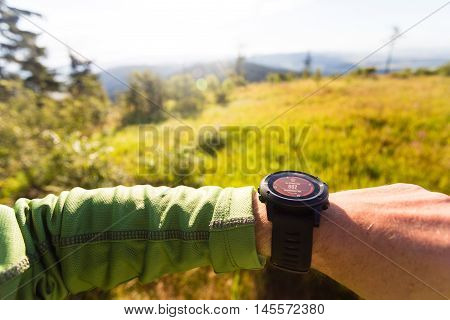 Hiker or traveler on mountain trail checking direction on electronic compass performance or heart rate pulse with smart watch. Travel sport training and fitness motivation inspiration outdoors.