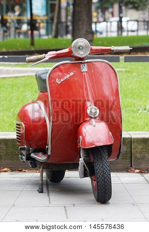 STOCKHOLM SWEDEN - SEPTEMBER 03 2016: Red retro vespa scooter parked in the park before the start of the Mods vs Rockers event at the Saint Eriks bridge Stockholm Sweden September 03 2016