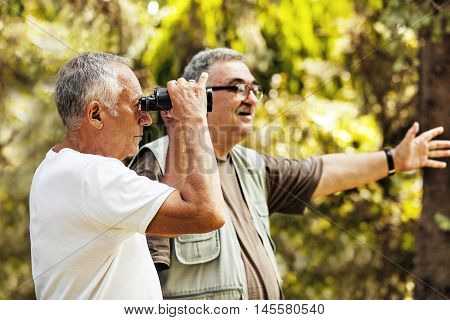 Two senior friends enyojing nature using binoculars.