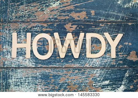 Word howdy written with wooden letters on rustic surface