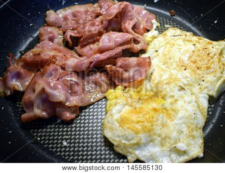 Bacon and eggs on a fried pan.