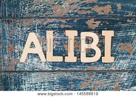 Word alibi written with wooden letters on rustic surface