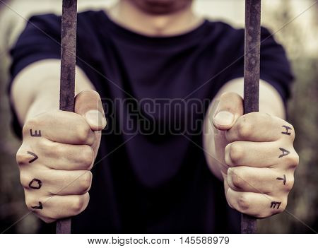 Man stretching his arms forward. Hands clenched into fists. In the hands of inscribed words "love" and "hate"