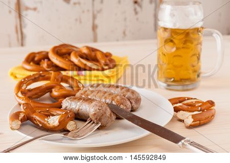Bavarian cooked sausage and pretzel on background with a glass of beer