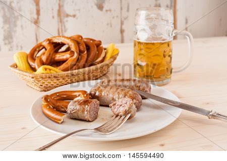 Bavarian cooked sausage and pretzel on a breadbasket and beer on background