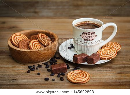 There are Cookies,Candy,Chocolate Peas,Poppy;Porcelain Saucer and Cap with Coffe,Tasty Sweet Food on the Wooden Background