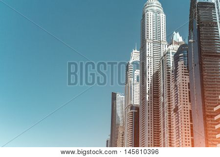 Multiple skyscrapers in sunny day, view from the bottom, blue sky background