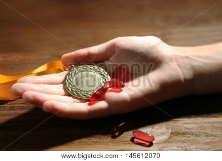 Female hand with pills and medal. Doping in sport concept
