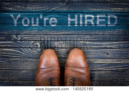 You're hired message and business shoes on wooden floor