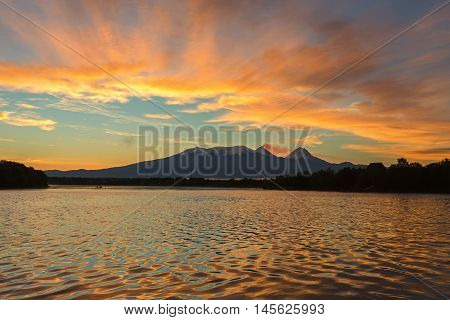 Beautiful sunrise over the volcanoes Kluchevskaya group with reflection in the river Kamchatka.