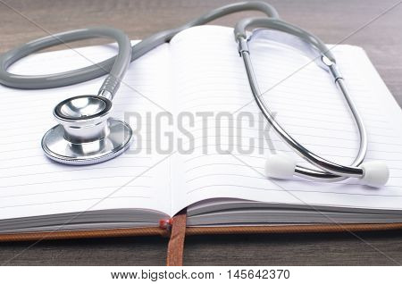 Stethscope on top of notebook with wooden background