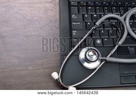Stethscope on top of laptop with wooden background