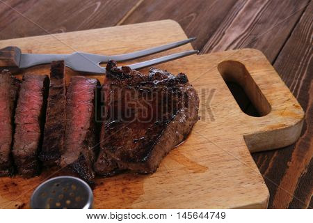 fresh roast red beef meat fillet mignon cutted on wooden plate with vintage fork many different kinds of dry spice over table