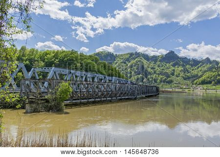 An old and new bridge crossing a big river whit mountains in background