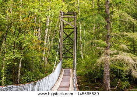 Photo of wooden suspention bridge in countryside.