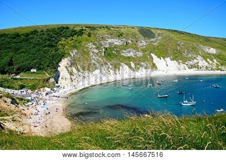 LULWORTH COVE, UNITED KINGDOM - JULY 19, 2016 - View looking down the hillside towards the cove with tourists enjoying the beach Lulworth Cove Dorset England UK Western Europe, July 19, 2016.