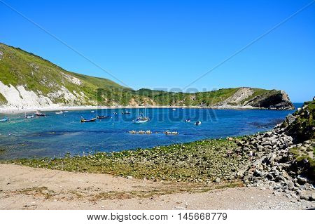 LULWORTH COVE, UNITED KINGDOM - JULY 19, 2016 - View of the beach and cove with boats moored offshore Lulworth Cove Dorset England UK Western Europe, July 19, 2016.