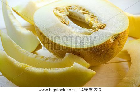 half and slices of ripe melon on a white background