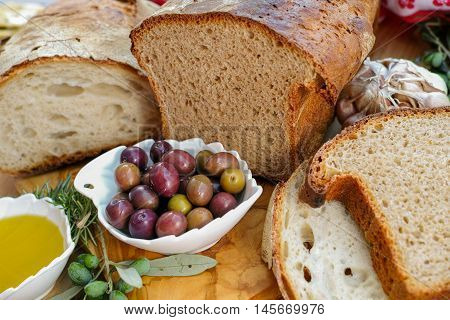 Traditional italian appetizer - fresh homemade bread extra virgin olive oil and olives on wooden background