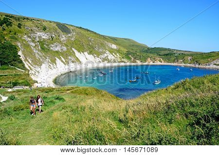 LULWORTH COVE, UNITED KINGDOM - JULY 19, 2016 - Elevated view of boats moored in the cove with tourists walking in the foreground Lulworth Cove Dorset England UK Western Europe, July 19, 2016.