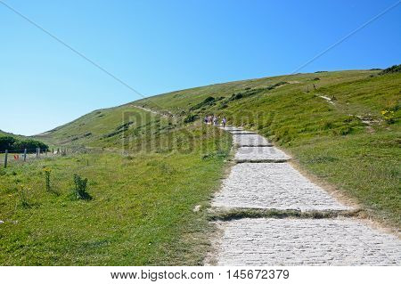 LULWORTH COVE, UNITED KINGDOM - JULY 19, 2016 - Tourists walking along a steep stepped pathway up the hillside Lulworth Cove Dorset England UK Western Europe, July 19, 2016.