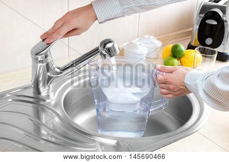 Man pours water into water filter jug