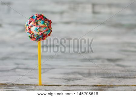 Decorated cake lollipop. Candy with glaze and sprinkles. Flavor of happy life. How to congratulate a kid.