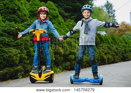 Happy boys riding on hoverboards or gyroscooters outdoor.