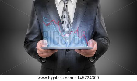 Cropped portrait of a businessman holding tablet with falling diagram above it. Economic and financial crisis. Business recession. Decline and setback.