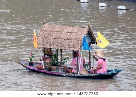 AYUTTHAYA, THAILAND - JULY 15, 2011: Pretty woman sitting show on the traditional boats in candle floating parade, the unique annual candle festival of Buddhist lent  in Lad Chado, Ayutthaya, Thailand.