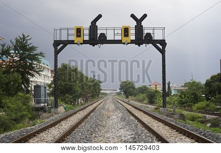 two parallel railway pass in a city with a railway traffic light