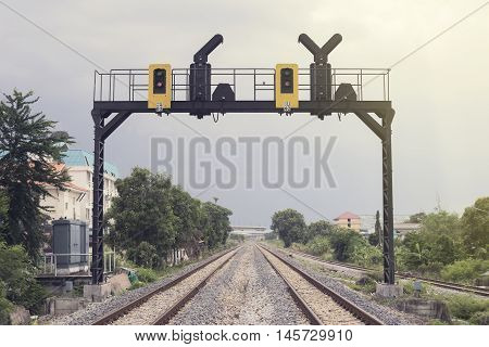 two parallel railway pass in a city with a railway traffic light
