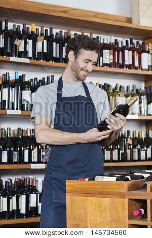 Salesman Reading Label Of Wine Bottle In Store