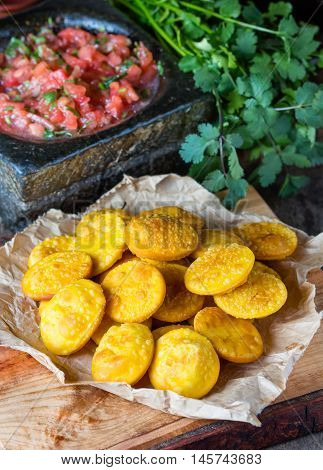 Sopaipilla. Latin American food. Traditional chilenian homemade pumpkin sopaipillas with typical mexican salsa - tomato sauce in stone mortar on rustic cutting board on wooden background