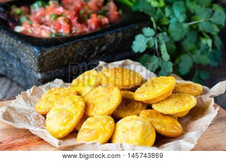 Sopaipilla. Latin American food. Traditional chilenian homemade pumpkin sopaipillas with typical mexican salsa - tomato sauce in stone mortar on rustic cutting board on wooden background