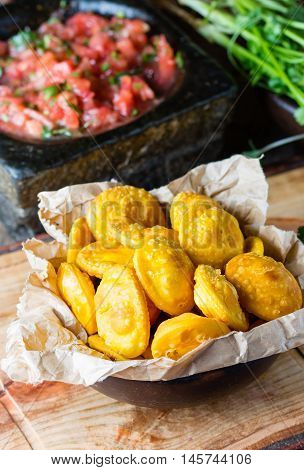Sopaipilla. Latin American food. Traditional chilenian homemade pumpkin sopaipillas with typical mexican salsa - tomato sauce in stone mortar on rustic cutting board on wooden background