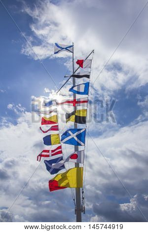 international maritime signal flags jn a flagpole against a blue sky