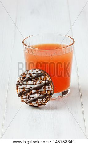 Grapefruit juice with chocolate cookies on a white wooden surface.