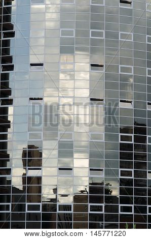 Skyscraper dark mirror glass surface reflecting cloudy sky