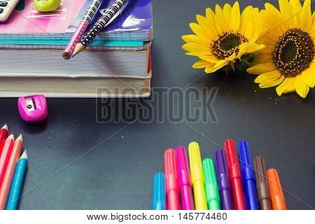 School supplies - notebooks and pens on chalkboard