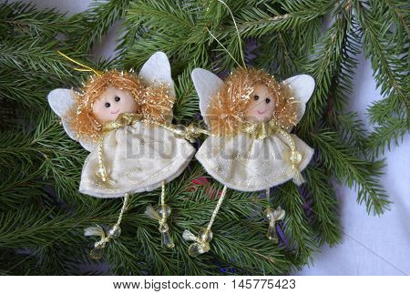 Christmas toys in the form of angels. Toys are located on a fir-tree. Angels in white clothes. Angels have golden hair