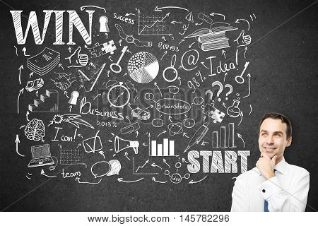 Thoughtful young businessman standing against concrete wall with creative business sketch. Leadreship and success concept
