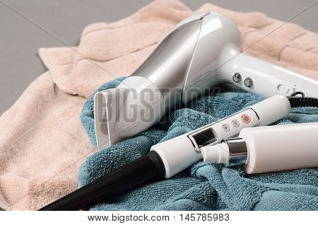 Hairstyling Tools (white Hairdryer, Hairspray, Cone Curling Wand) On Beige And Greenish-blue Towels