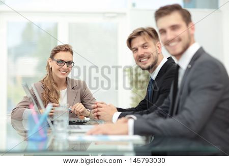 Happy business people looking at camera in office and  using com