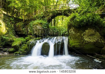 A beautiful location called Mullerthal trail with a bridge over a small waterfall in Luxembourg