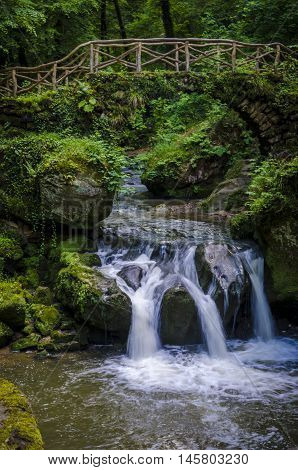 A beautiful location called Mullerthal trail with a bridge over a small waterfall in Luxembourg