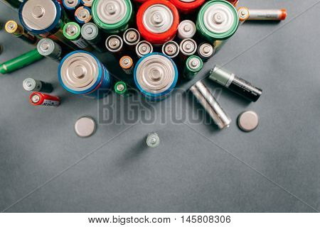 Top view on portable batteries on gray background, free space. Colorful energy composition, variety of different kinds of accumulators, copy space
