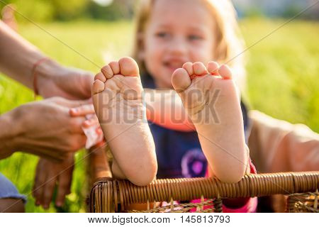 Little girls feet sitting in a wicker basket on a sunny day in the park